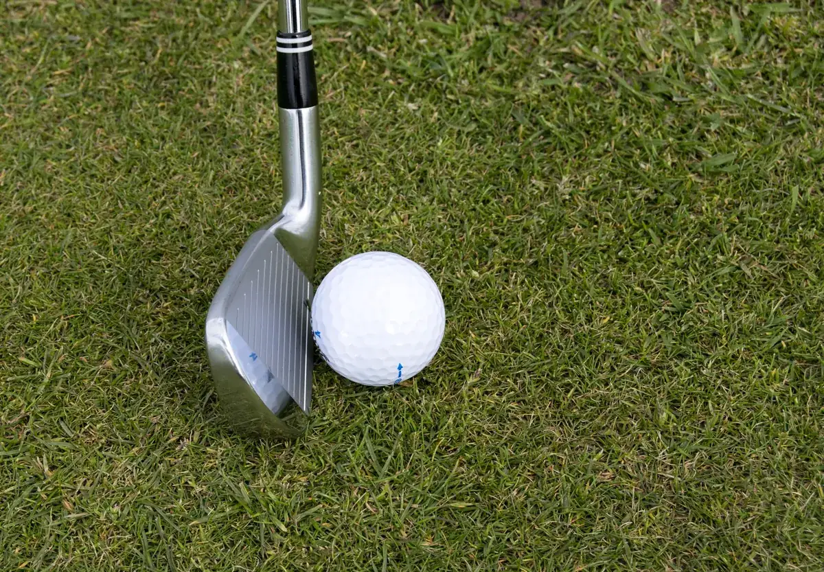 Golf wedge and ball on green turf, representing golf and ski massage in Salt Lake City