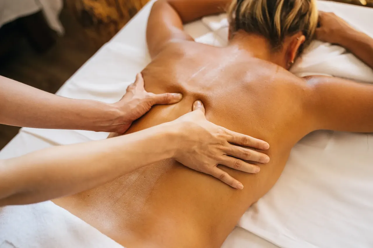 Massage therapist working along the shoulder blade of a client lying face down